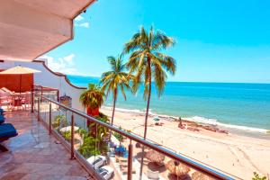 Elle comprend un balcon offrant une vue sur la plage bordée de palmiers et l'océan. dans l'établissement Vallarta Shores Beach Hotel, à Puerto Vallarta