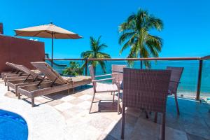 um pátio com cadeiras e um guarda-sol e o oceano em Vallarta Shores Beach Hotel em Puerto Vallarta