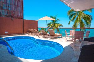 Vallarta Shores Beach Hotel في بويرتو فايارتا: مسبح مع كراسي وطاولات والمحيط