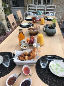 una mesa de madera con comida y bebidas. en Le mas Normand en Ver-sur-Mer