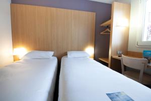 A bed or beds in a room at Kyriad Direct Clermont Ferrand Nord Gerzat