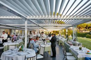 un restaurante con mesas blancas y gente sentada en mesas en Gallia Palace Hotel - Relais & Châteaux en Punta Ala