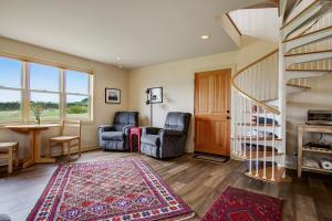 a living room with a staircase and chairs and a rug at Headlands View in Mendocino