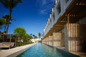 a swimming pool next to a building with palm trees at Princess Family Club Bavaro - All Inclusive in Punta Cana