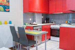 eine Küche mit roten Schränken und einem Tisch mit Stühlen in der Unterkunft City Stay Alexandras Av. in Athen