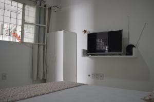 um quarto branco com uma televisão e uma cama em Pousada Marazul em Maceió