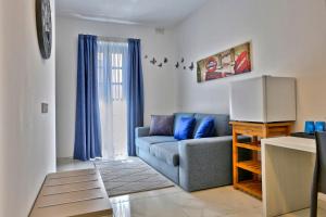 een woonkamer met een blauwe bank en blauwe gordijnen bij The Exiles Hotel in Sliema