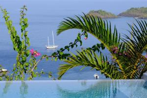 una piscina con un barco en el agua en Sunset Palm - Villa Créole avec piscine face au coucher de soleil et à la réserve Cousteau, en Bouillante