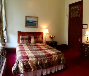 ein Schlafzimmer mit einem Bett, zwei Lampen und einer Tür in der Unterkunft The Monarch Hotel in Port Townsend