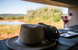a hat and headphones sitting on a table with a drink at Molori Safari in Derdepoort