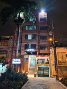 a hotel at night with a palm tree in front of it at Hotel Suramericana in Medellín