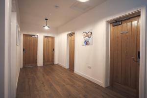 pusty korytarz z drewnianymi drzwiami i drewnianą podłogą w obiekcie Herongate Apartments w mieście Hungerford