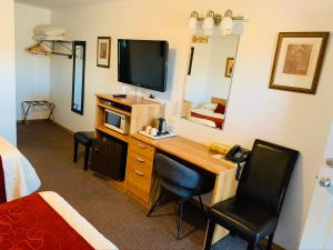 Zimmer mit einem Schreibtisch, einem TV und einem Bett in der Unterkunft Bo-Mark Motel in North Bay