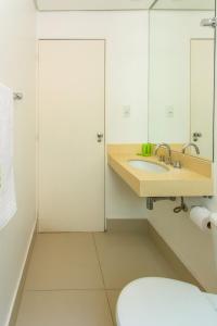 a bathroom with a sink and a toilet and a mirror at VOA San José Palace Hotel in Osasco