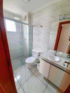biała łazienka z toaletą i umywalką w obiekcie Apartamento Mirim Praia Grande w mieście Praia Grande