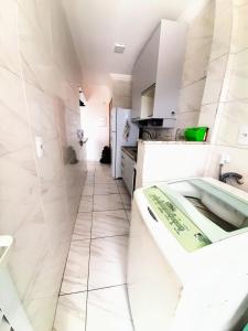 a white bathroom with a tub and a sink at Apartamento Mirim Praia Grande in Praia Grande