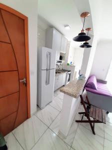 a kitchen with a white refrigerator and a table at Apartamento Mirim Praia Grande in Praia Grande