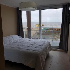 1 dormitorio con cama y ventana grande en Ocean Blue en San Clemente del Tuyú