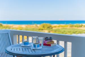 een blauwe tafel met twee kopjes en een boek en twee glazen bij Villa Smaragdi - Private Sea View Villa in Falasarna
