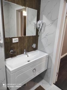 uma casa de banho com um lavatório branco e um espelho. em ЖОМАРТ em Aqtöbe