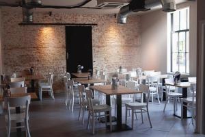 a dining room with tables and chairs and a brick wall at Vakantiewoning Weverijstraat met strandcabine in Domburg