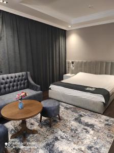 een slaapkamer met een bed, een bank en een tafel bij ЖОМАРТ in Aqtöbe