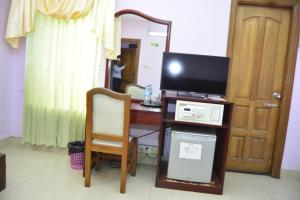 Zimmer mit einem Schreibtisch, einem TV und einem Spiegel in der Unterkunft Naba Inn in Chittagong