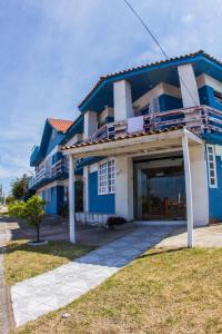 a blue and white house with a garage at Hotel Recanto do Mar in Capão da Canoa