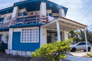 a blue and white house with a car parked in front at Hotel Recanto do Mar in Capão da Canoa