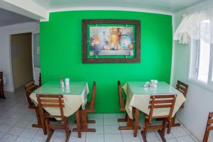 a dining room with two tables and a green wall at Hotel Recanto do Mar in Capão da Canoa