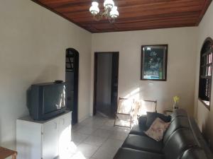 a living room with a couch and a tv at Chácara em Serra Negra in Serra Negra