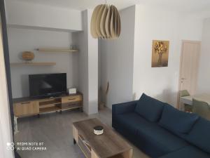 a living room with a blue couch and a tv at Lavender and Sea in Nea Potidaea