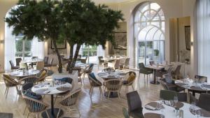 ein Restaurant mit Tischen, Stühlen und einem Baum in der Unterkunft Holiday Inn Resort le Touquet, an IHG Hotel in Le Touquet-Paris-Plage