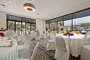 a banquet hall with white tables and chairs and windows at Holiday Inn and Suites Charleston West, an IHG Hotel in Charleston