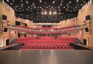 un auditorio vacío con asientos y luces rojas en voco® Villach, an IHG Hotel, en Villach