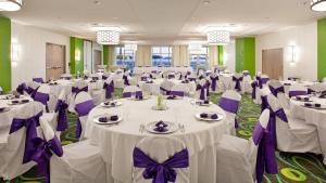 a banquet hall with white tables and purple bows at Holiday Inn Resort Fort Walton Beach by IHG in Fort Walton Beach +133 photos