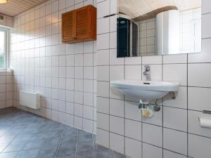 ein weiß gefliestes Bad mit einem Waschbecken und einem Spiegel in der Unterkunft 8 person holiday home in Odder in Odder
