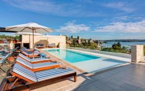 a pool with lounge chairs and an umbrella on a building at InterContinental Sydney Double Bay by IHG in Sydney