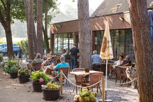 a group of people sitting at tables in a garden at Vakantiewoning Zavelbos in Maaseik