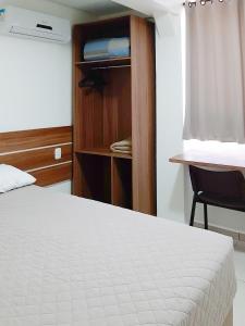 a bedroom with a bed and a chair and a closet at Tri Hotel Smart Chapecó in Chapecó