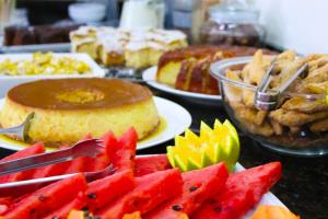 a table topped with plates of cake and fruit at Tri Hotel Smart Chapecó in Chapecó