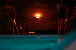 a person standing at the edge of a swimming pool at night at Sollaris Ecopousada in Japaratinga