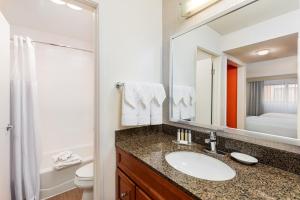a bathroom with a sink and a mirror and a toilet at Clementine Hotel & Suites Anaheim in Anaheim