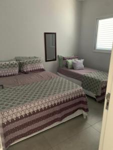 a bedroom with two beds and a mirror at Morada da Praia - Casa in Bertioga