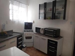 Il comprend une petite cuisine équipée d'un four micro-ondes et d'une cuisinière. dans l'établissement Apartamento Carrinho do Kuko n 309, à Praia Grande