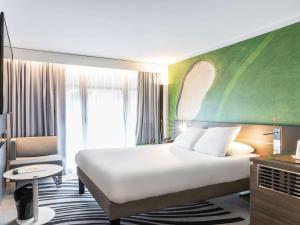 a hotel room with a large bed and a chair at Novotel Deauville Plage in Deauville