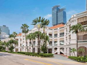 een wit gebouw met palmbomen voor een straat bij Raffles Singapore in Singapore