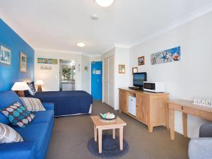 uma sala de estar com um sofá azul e uma televisão em Calypso Plaza Resort Unit 215 em Gold Coast