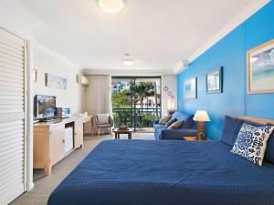 Dormitorio azul con cama y sofá en Calypso Plaza Resort Unit 215 en Gold Coast