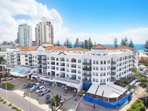 eine Luftansicht auf ein großes weißes Gebäude mit einem Parkplatz in der Unterkunft Calypso Plaza Resort Unit 215 in Gold Coast